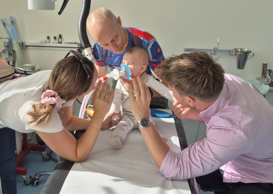 Jeg giver rolig maskebedøvelse til en baby, mens forældrene holder barnets hænder